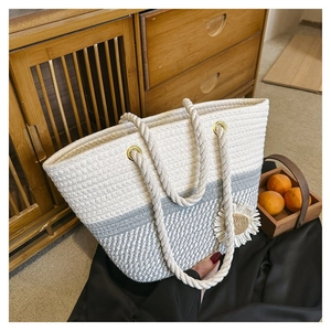 Detailed shot of woven tote bag with daisy pendant and rope handle in natural setting