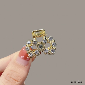 Detailed view of 2cm mini golden metal hair claw clip with sparkling rhinestones