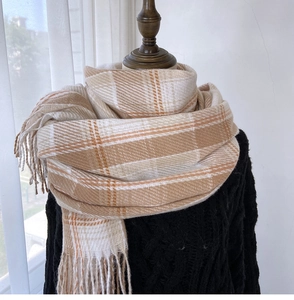 Detail of classic plaid scarf with soft fringe edges in beige and caramel tones