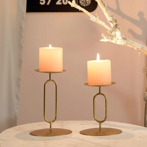 Golden minimalist oval ring metal candle holders set on a white marble table