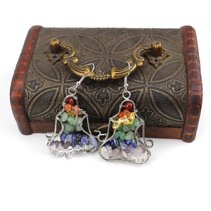 Macro shot of handmade chakra stone yoga earrings hanging on a vintage wooden jewelry box
