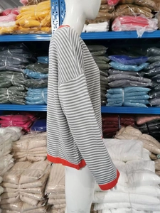 Détail d'un pull rayé gris avec col et poignets côtelés orange contrastés