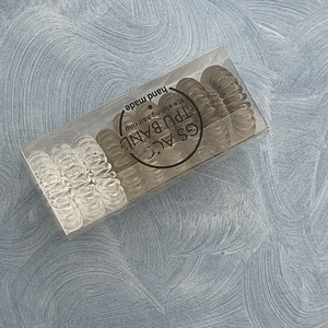 Detail view of brown and clear TPU telephone wire hair ties in a transparent box