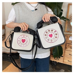Detail view of the quirky retro telephone handset handle and heart dial on a white PU crossbody bag