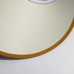 Macro shot of the stitched yellow fabric brim and cream leather texture of the sun visor