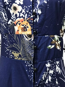 Détail de la robe fleurie bleu foncé montrant l'imprimé jaune et les boutons noirs