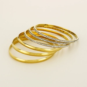 Detail of six layered gold-plated bangles with polished finish and micro-pave crystals