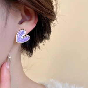 Close-up of purple heart enamel earring with golden edges worn on a model's ear