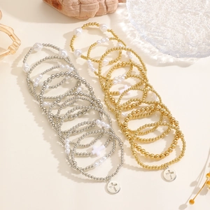 Dettaglio di braccialetti con perline bohémien, ciondoli a croce e perle metalliche