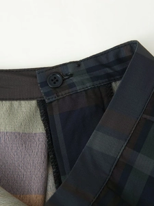 Vue macro détaillée du pantalon à carreaux montrant les coutures et le bouton bleu