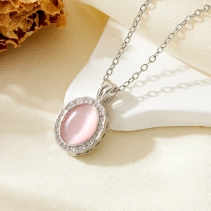 Detail of silver chain necklace with pink cat-eye stone pendant and pavé zircon border