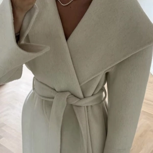 Elegant white wool cashmere coat with belted waist and large lapels in a sleek minimal style