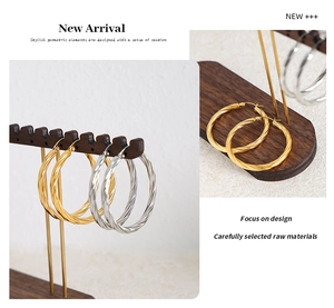 Detailed close-up of textured twist hoop earrings in gold and silver stainless steel