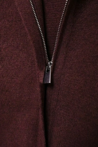 Vue rapprochée du zip métallique sur un cardigan en maille bordeaux de texture laine