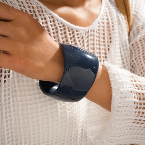 Detail of chunky dark blue resin cuff bracelet on model wearing white knit sweater