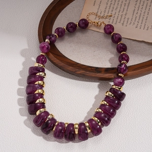 Detail of purple acrylic marble-textured beads with golden metal spacers on a vintage necklace