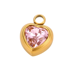 Macro shot of gold-plated heart pendant with pink gemstone and polished metal edges