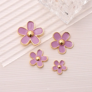 Detail of purple enamel flower charms in multiple sizes with gold-plated alloy edges
