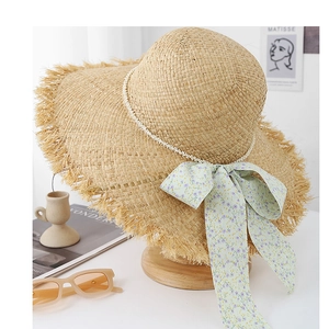 Détail du chapeau de soleil en raphia avec bande de perles et ruban à fleurs