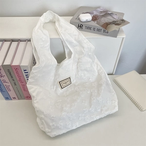 Detailed view of white jacquard tote bag with 3D floral textures and fabric patch