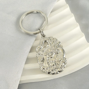 Détail d'un porte-clés en acier inoxydable argenté avec pendentif dragon sur fond de soie