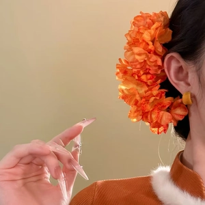 Elegant orange fabric flower hair pin and matching earrings worn with classic dress