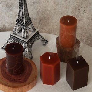 Detail view of textured cylindrical and hexagonal scented candles in earthy brown tones