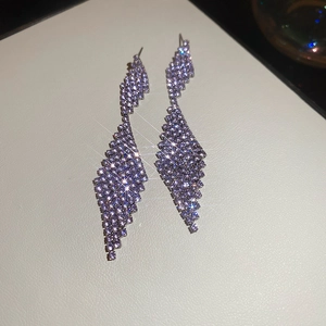 Macro shot of long purple crystal geometric drop earrings with sparkling starlight effect