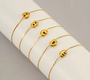 Detail view of five gold 18K plated stainless steel initial letter pendant bracelets