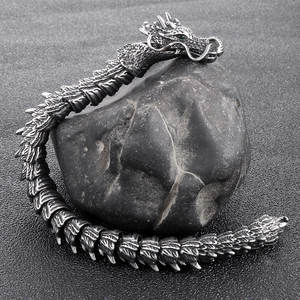 Detailed view of stainless steel dragon bracelet with green gemstone eyes on rock
