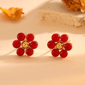 Close-up of red flower stud earrings with cat eye stone and gold base set on warm background