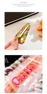 Detail of rainbow woven texture on golden duckbill clip with pink CUTE letter resin decor
