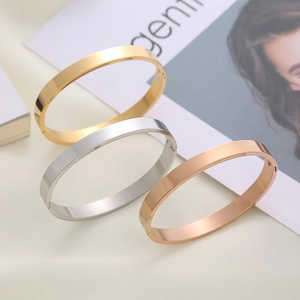 Minimalist stainless steel cuff bracelets in gold, silver, and rose gold on a trendy magazine