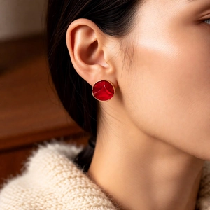 Close-up of vintage-style red round enamel stud earrings with gold-toned metal edging