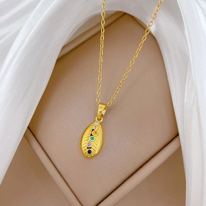 Macro shot of gold-plated titanium necklace with colorful gems on an oval leaf pendant