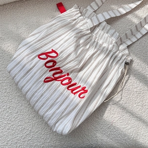 Close-up of striped canvas tote bag with red Bonjour embroidery and drawstring closure