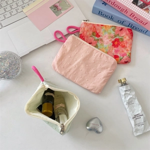 Pink polka dot and mint green floral cosmetic bags with zip and laptop background
