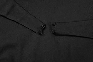 Dettaglio della chiusura con ganci su un abito lungo in maglia nera a rete