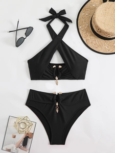 Detailed flat lay of black bikini with golden metal pendants and holiday accessories
