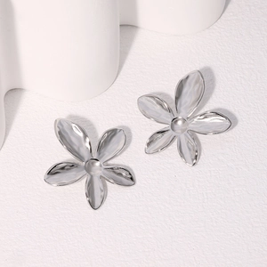 Détail des boucles d'oreilles fleur à cinq pétales en argent avec texture de métal martelé