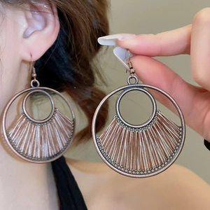 Macro shot of large bohemian round woven drop earrings with retro bronze alloy frame