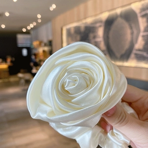 Close-up of a beige rose-shaped hair scrunchie made from soft satin fabric