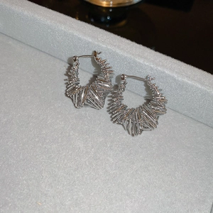 Macro detail of silver geometric hoop earrings with textured wire woven design