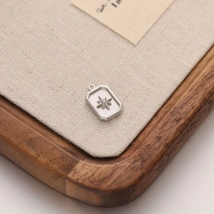 Macro shot of silver rectangular pendant featuring a starburst pattern and clear zircon