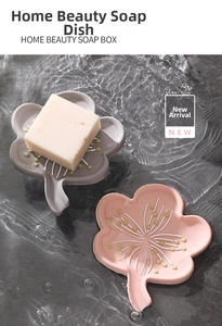 Floral silicone soap dishes in pink and gray with drain design on bathroom tile