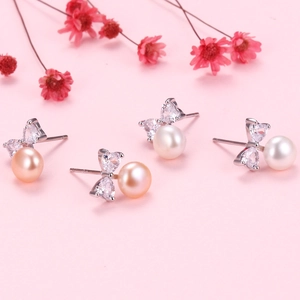 Elegant silver bow stud earrings featuring white pearls and sparkling cubic zirconia
