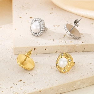 Detail of gold and silver pearl stud earrings with textured bezel and crystal accents