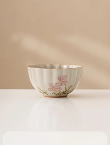 Detail view of ash gray daisy ceramic tea cup with wavy rim and pink floral patterns