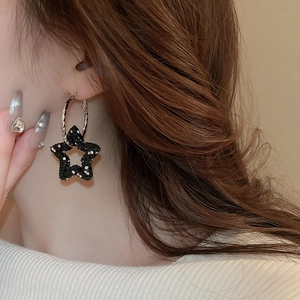 Dark style silver needle hoop earrings featuring rhinestone star pendants on a model