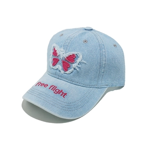 Close-up of light blue denim baseball cap with pink butterfly patch and Free flight embroidery